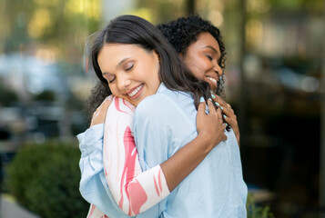 Friendship Concept. Two Young Women Hugging Each Other Outdoors And Smiling