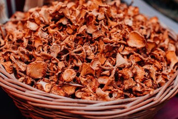 Natural background of dried beige chanterelle mushrooms in the wicker basket. Harvest and thanksgiving concept.