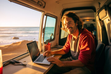 Handsome young digital nomad using a laptop computer in camper van on sunny day. Man working remotely with his laptop. Digital nomadic life. - obrazy, fototapety, plakaty
