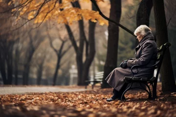 Photo sur Plexiglas Destinations Beautiful senior lady sitting alone on a bench in city park on autumn day. Elderly woman enjoying nice fall weather.