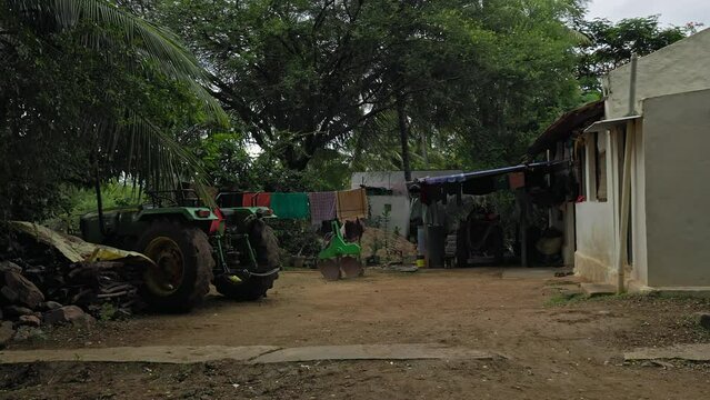 A video of tractors parked in front of an old house in a rural Indian village
