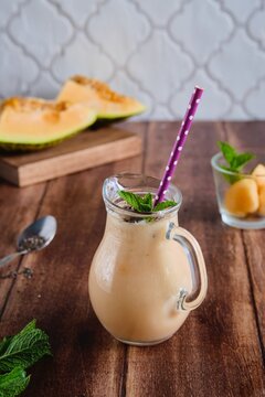 Melon smoothie with chia seeds in a serving jug on a brown wooden background. Melon recipes. Refreshing soft drinks.