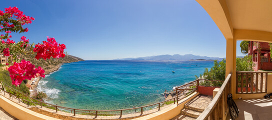 Fototapeta na wymiar Panoramic view of the turquoise mediterranean sea at the island of Crete, Greece, near Agios Nikolaos, with pink bougainville flowers and fins