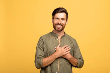 Gratitude concept. Thankful cheerful middle aged man keeping hands on chest and smiling, expressing...