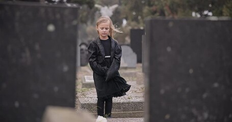 Sad, death or kid in cemetery for funeral. spiritual service or grave visit for respect in Christian religion. Mourning, tomb or depressed girl child outside in graveyard for grief, loss or farewell
