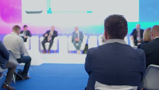The audience listens to lecturers at a business conference. Rear view between rows. A small number of people. The concept of education and public speaking.