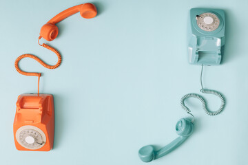 Two phones with the headset up. Retro colour telephones. Copy space.