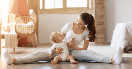 Athletic young mother stretching with her little baby at home