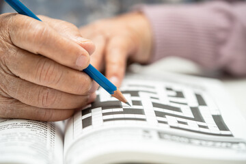 Alzheimer disease AD, Asian elderly woman playing sudoku puzzle game to practice brain training for dementia prevention.