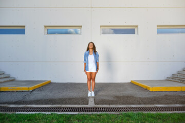 Young woman in casuals standing outside building