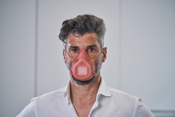 Serious adult male in protective mask looking at camera
