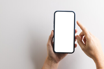 Hands of caucasian woman holding smartphone with blank screen and copy space on white background