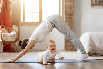 Young mother and little baby doing yoga exercises at home