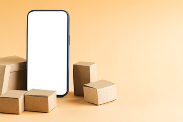 Smartphone with blank screen and cardboard boxes with copy space on yellow background