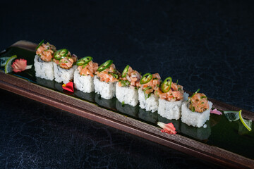 Appetizing sushi rolls served with salmon in tray