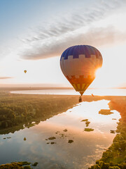Hot air balloon is flying at sunrise or sunset. Aerial drone view