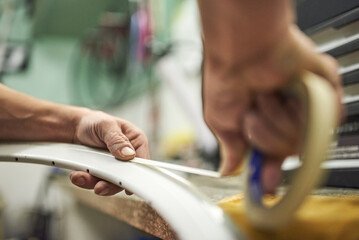 Hands preparing a bicycle wheel with masking tape to paint it.
