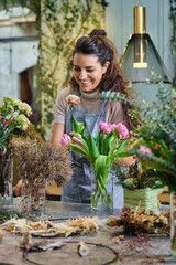 Woman composing flower bouquet and smiling
