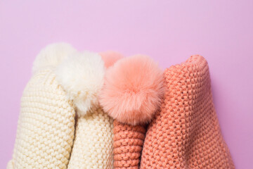 Knitted hats and scarves close-up on lilac background