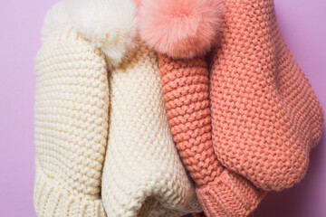 Knitted hats and scarves close-up on pink background