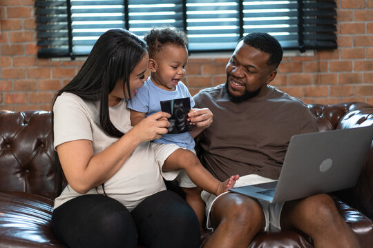 Happy family African American father and pregnant Asia mother with happy baby son at home 