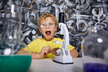 Cute little scientist makes his first scientific discoveries with help of real microscope on...