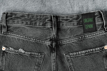 Black jeans labeled ORGANIC DENIM. Sustainable fashion, conscious consumption, trendy clothing.