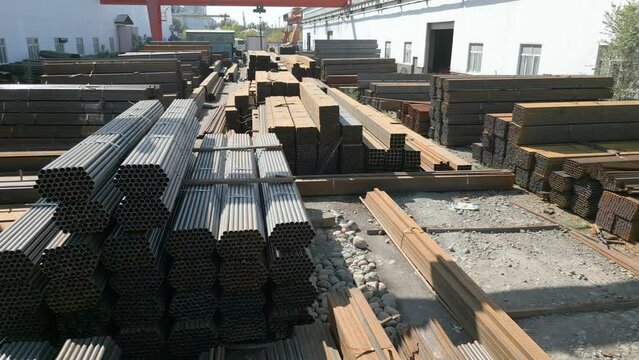 Aerial view of galvanized iron pipes stack and steel rectangular bars of metal