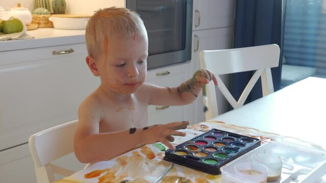 cute little boy toddler child draws with watercolors painting his face