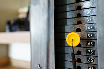 Stacked steel - metal plates in the weight training exercise machine in the indoor gym. Close up view of iron stacked weight plates of workout machine gym.