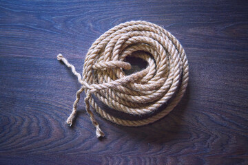 Coil of jute rope on the background of a brown wooden surface.