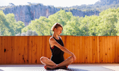 Young woman doing stretching exercises on the street.  A beautiful girl in sportswear is doing yoga.