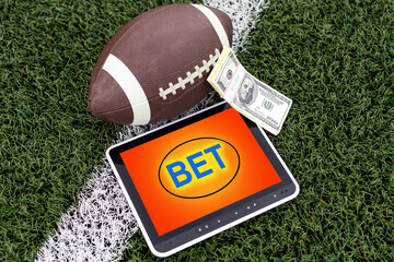 tablet pc with app for sport bets, stacks of banknotes and a football ball, concept of online bets (3d render)