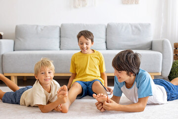 Happy positive children, tickling on the feet, having fun together, boy brothers at home having...