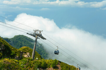 Cable car with a cabin descending down a mountain with people.