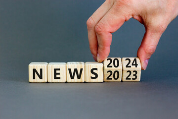 2024 News new year symbol. Businessman turns a wooden cube and changes words News 2023 to News 2024. Beautiful grey table grey background, copy space. Business 2024 news new year concept.
