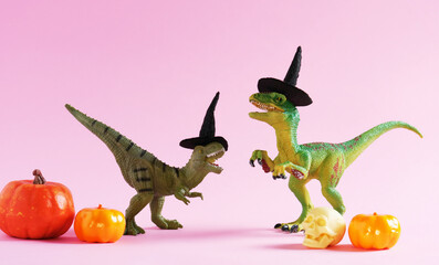 Two cute happy green dinosaurs with pumpkins on pink background.