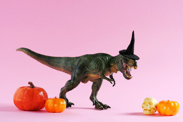 Happy green tyrannosaurus with pumpkins on pink background.