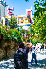 A boy is taking a photo of the Pena Palace in Sintra.