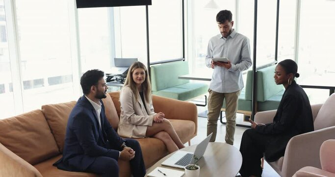Multi-ethnic teammates brainstorm, take part in briefing gathered in modem coworking space, to discuss joint project, share creative ideas, planning cooperation looking friendly engaged in teamwork