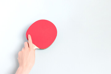 Female hand hold racket for ping pong on a blue background. Composition with place for text.