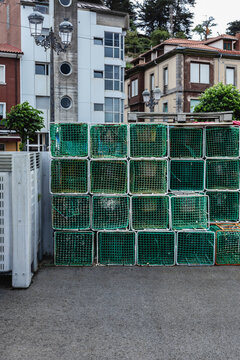 Green fishing traps piled up in a harbor in a small town in northern Spain. Vertical image