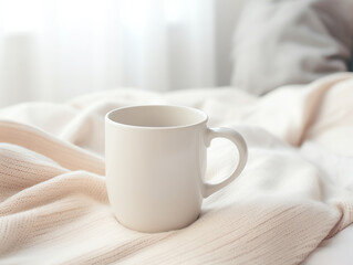 Blank empty white coffee mug mockup on warm knitted clothes in autumn and winter season