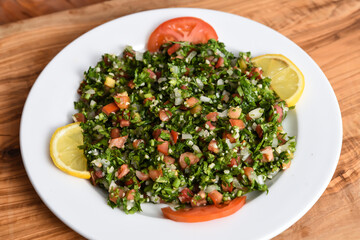 Tabbouleh salad with tomato, cucumber, green Coriander, onion and lemon served in dish isolated on wooden table top view middle eastern appetizers food