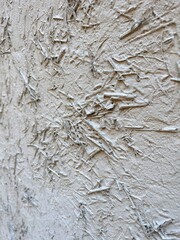 Textured background. Wall painted with white paint. White wall is painted with hay and rice straw. Abstract background with old white plaster. Grey color background. Vertical composition