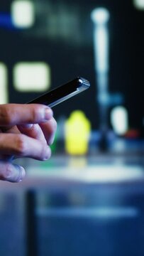 Vertical video Close up shot of aimless man strolling around city streets at night, chatting with his buddies using smartphone in urban setting. Carefree person enjoying empty town with no cars, using