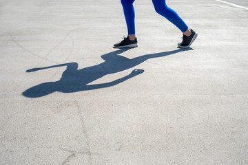 shadow of a woman athlete jogger in road