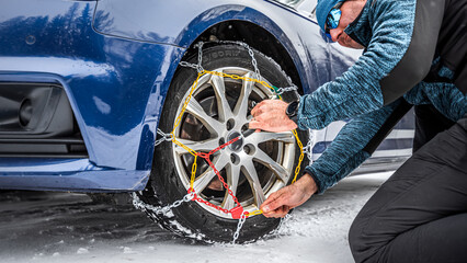 Putting snow chains on the front wheel of the drive axle. - obrazy, fototapety, plakaty