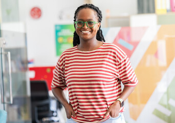 In her college office, a determined black female student stands confidently, a beacon of empowerment and knowledge, ready to conquer academic challenges and embrace her future.