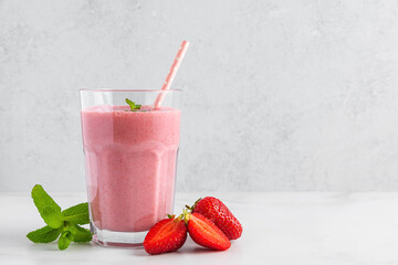 Strawberry smoothie in a glass with straw, fresh berries and mint. Summer refreshing drink. Healthy diet food